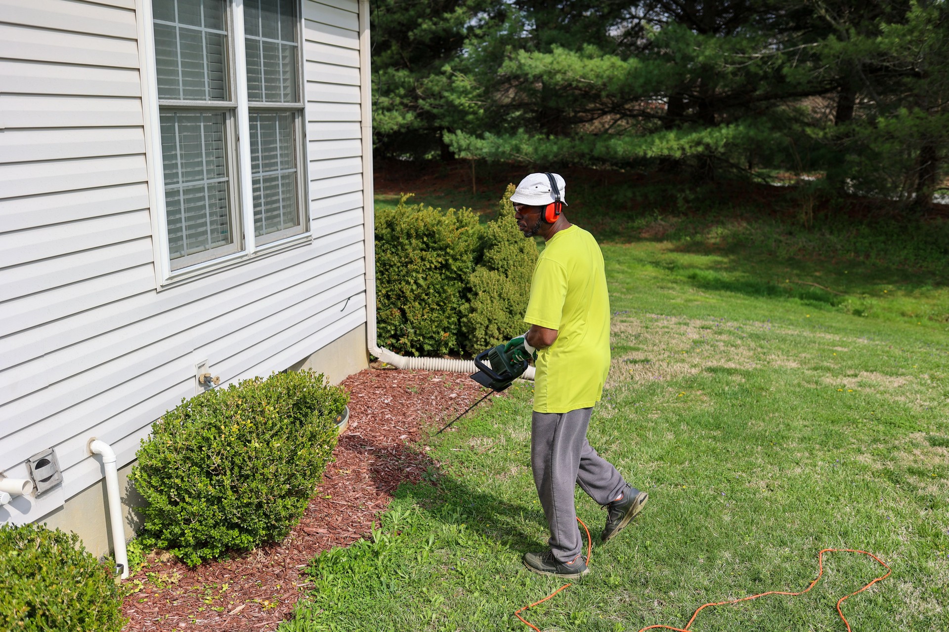A portrait of a black man trimming hedges
